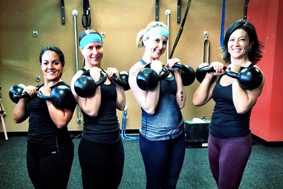 Team of women in gym holding kettlebells